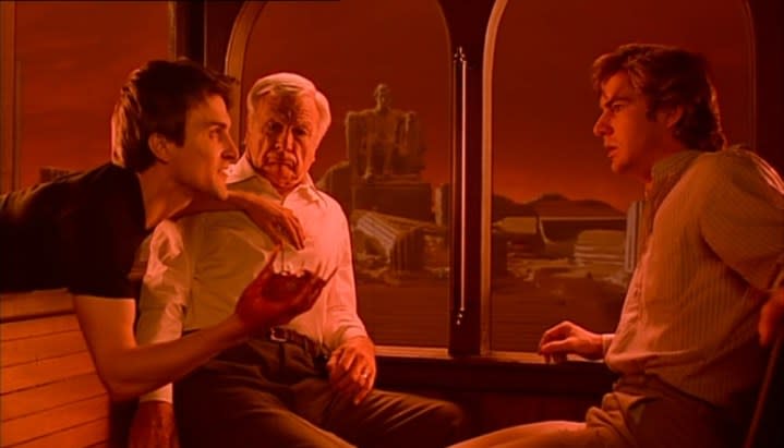 Three men sit on a train in Dreamscape.