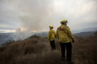 FILE - Firefighters watch as smoke rises from a wildfire in Fallbrook, northern San Diego County, Calif., Thursday, Dec. 24, 2020. Environmental groups have been arguing in California courts that developers are not fully considering the risks of wildfire and choked evacuation routes when they plan housing developments near fire-prone areas. (AP Photo/Ringo H.W. Chiu, File)