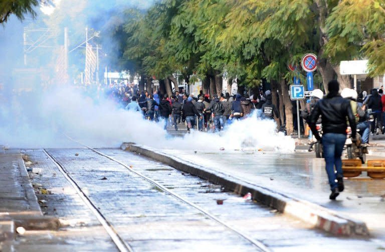 Tunisian protesters run away after police fired tear gas during a demonstration following the funeral of assassinated opposition leader Chokri Belaid in Tunis, on February 8, 2013