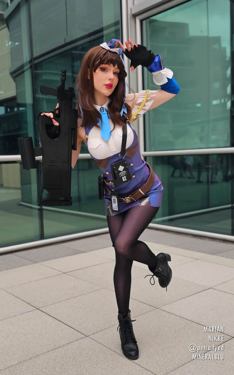 A Marian cosplayer stands on one foot while holding a gun.