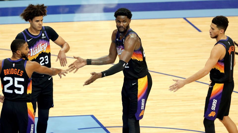 Phoenix Suns center Deandre Ayton, middle, is congratulated by Mikal Bridges (25), Cameron Johnson (23) and Devin Booker (1) after hitting a free throw during the second half of the team's NBA basketball game against the Houston Rockets on Wednesday, Jan. 20, 2021, in Houston. (AP Photo/Michael Wyke).