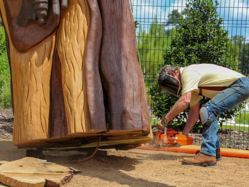 Tallahassee artist John Birch works to place a one of three artworks formed from live oak wood stumps along the Capital Cascades Trail in October, 2023.