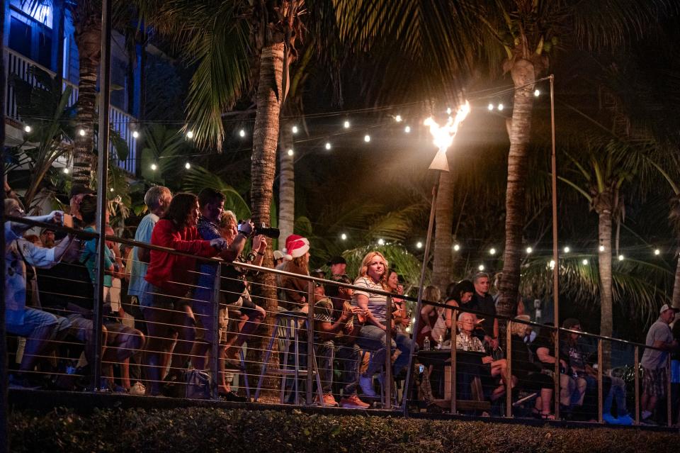 A crowd watches as illuminated and decorated boats pass by during the St. Lucie County Christmas Boat Parade on Saturday, Dec. 9, 2023, at Square Grouper Tiki Bar in Fort Pierce. The event was presented by the Marine Industries Association of the Treasure Coast Inc. and co-hosted by the Fort Pierce Yacht Club and Paella King.
