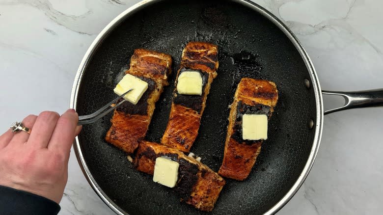 hand putting butter on salmon