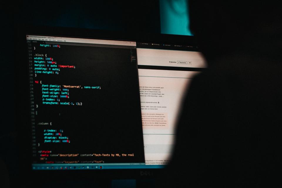 A person working on a laptop computer in a dark room.