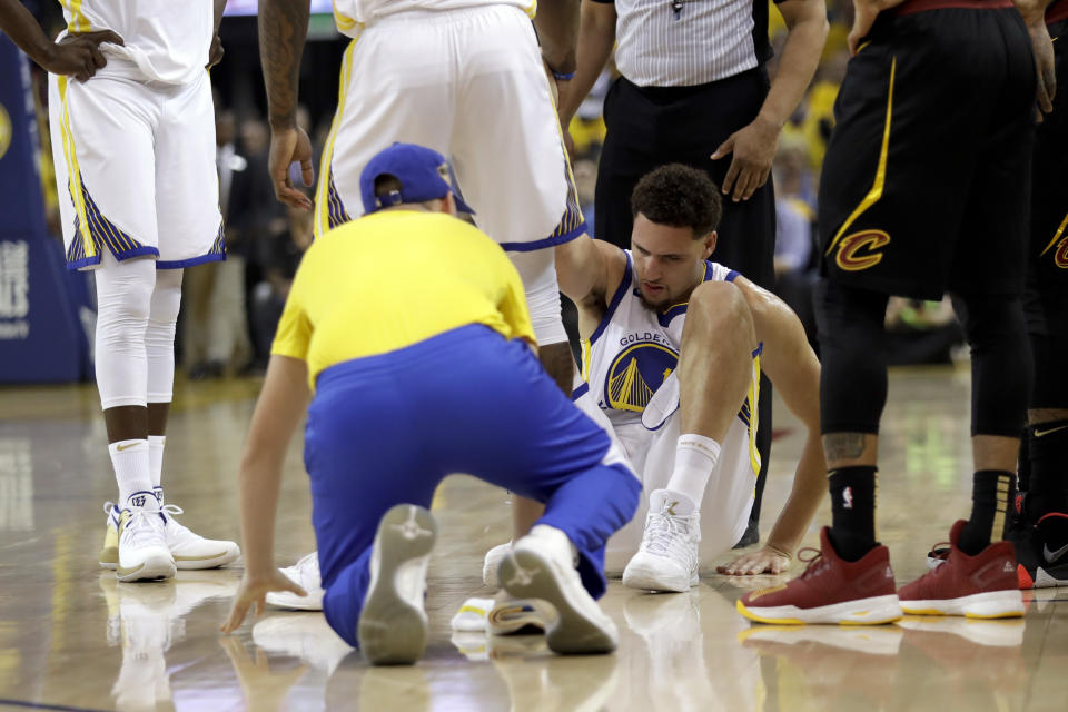 Golden State Warriors guard Klay Thompson is helped off the floor during the first half of Game 1 Thursday night. (AP)