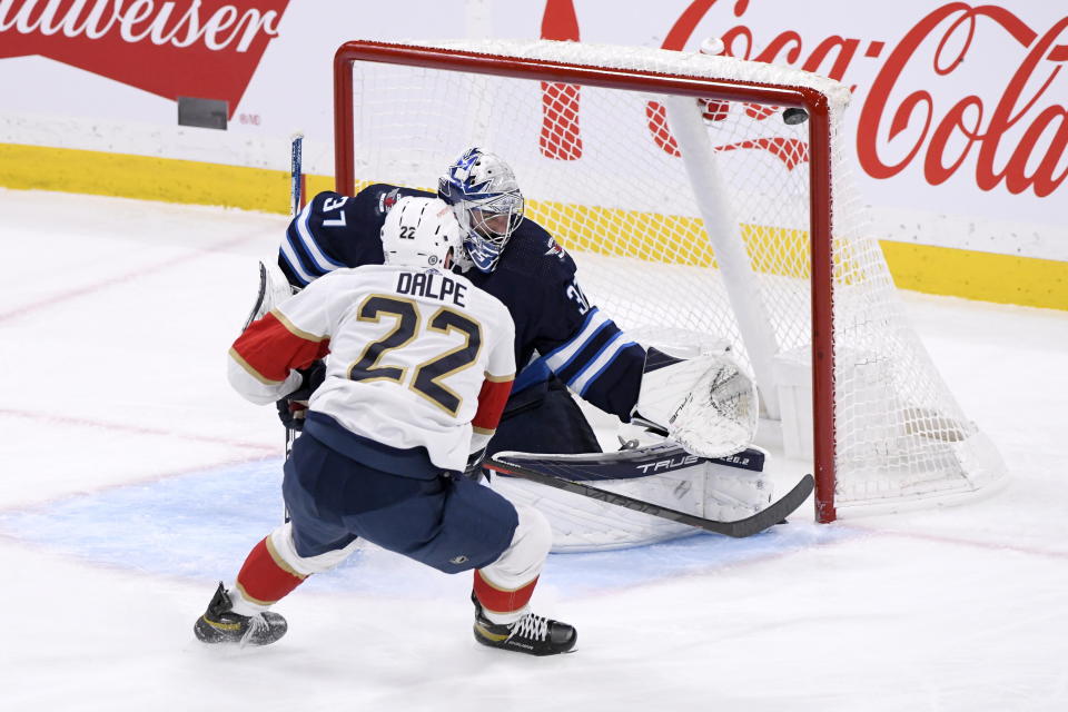 Florida Panthers' Zac Dalpe (22) scores on Winnipeg Jets goaltender Connor Hellebuyck (37) during the third period of an NHL hockey game Tuesday, Dec. 6, 2022, in Winnipeg, Manitoba. (Fred Greenslade/The Canadian Press via AP)