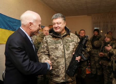 Ukrainian President Petro Poroshenko (R) shakes hands with U.S. Senator John McCain during a meeting with Ukrainian servicemen in Shirokino settlement near Mariupol, Ukraine, December 31, 2016. Mikhail Palinchak/Ukrainian Presidential Press Service/Handout via REUTERS