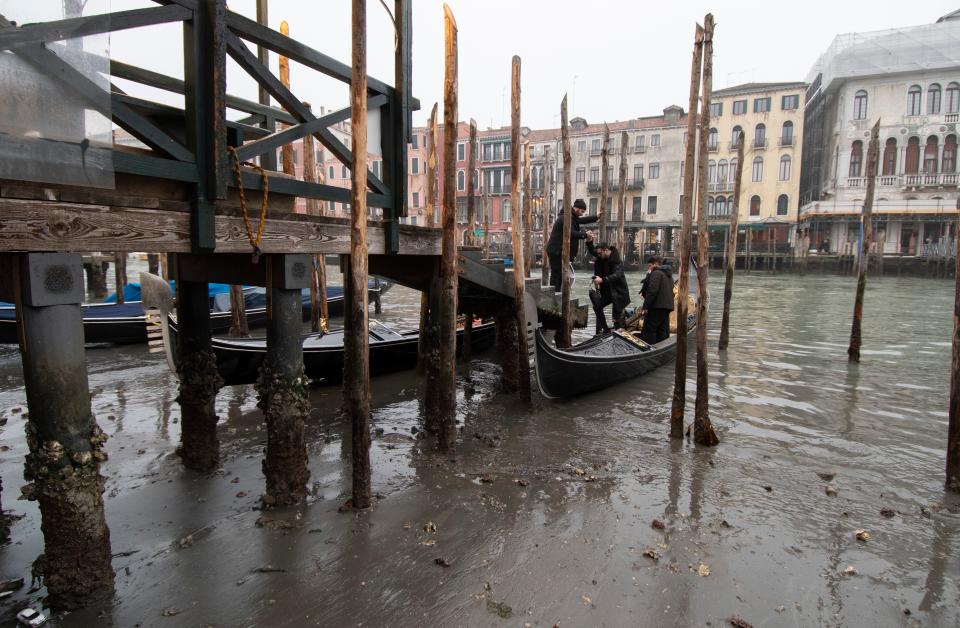 Passengers get off a gondola docked along a canal during a low tide in Venice, Italy, Tuesday, Feb. 21, 2023. Some of Venice's secondary canals have practically dried up lately due a prolonged spell of low tides linked to a lingering high-pressure weather system.