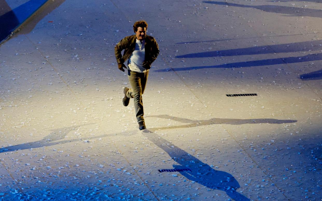 Tom Cruise runs across the stage during the closing ceremony