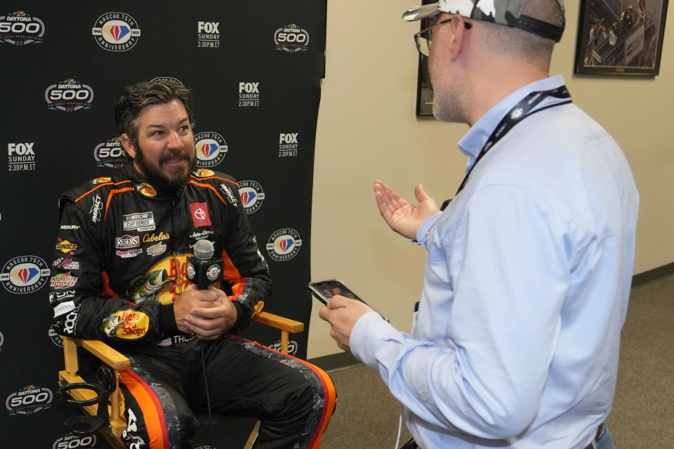 Martin Truex Jr., left, speaks with a foreign journalist during NASCAR Daytona 500 auto race media day at Daytona International Speedway, Wednesday, Feb. 15, 2023, in Daytona Beach, Fla. (AP Photo/John Raoux)