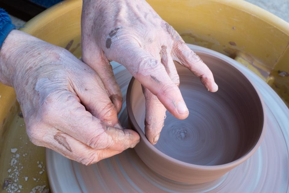 Hands on a pottery wheel spinning clay