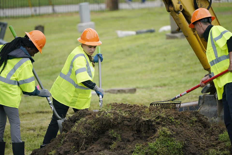 Workers rake through dirt as excavation begins at Oaklawn Cemetery in a search for victims of the Tulsa Race Massacre believed to be buried in a mass grave, Tuesday, June 1, 2021, in Tulsa, Okla. (AP Photo/Sue Ogrocki)