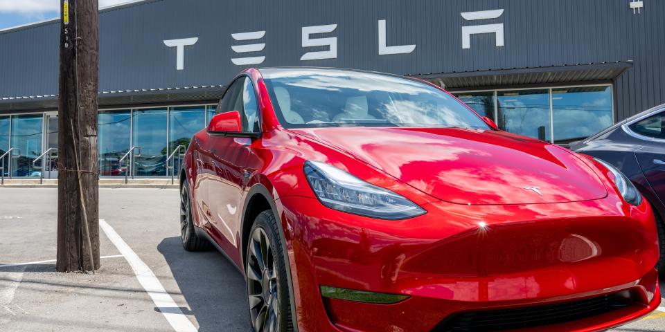 A red Tesla Model Y seen outside a Tesla showroom