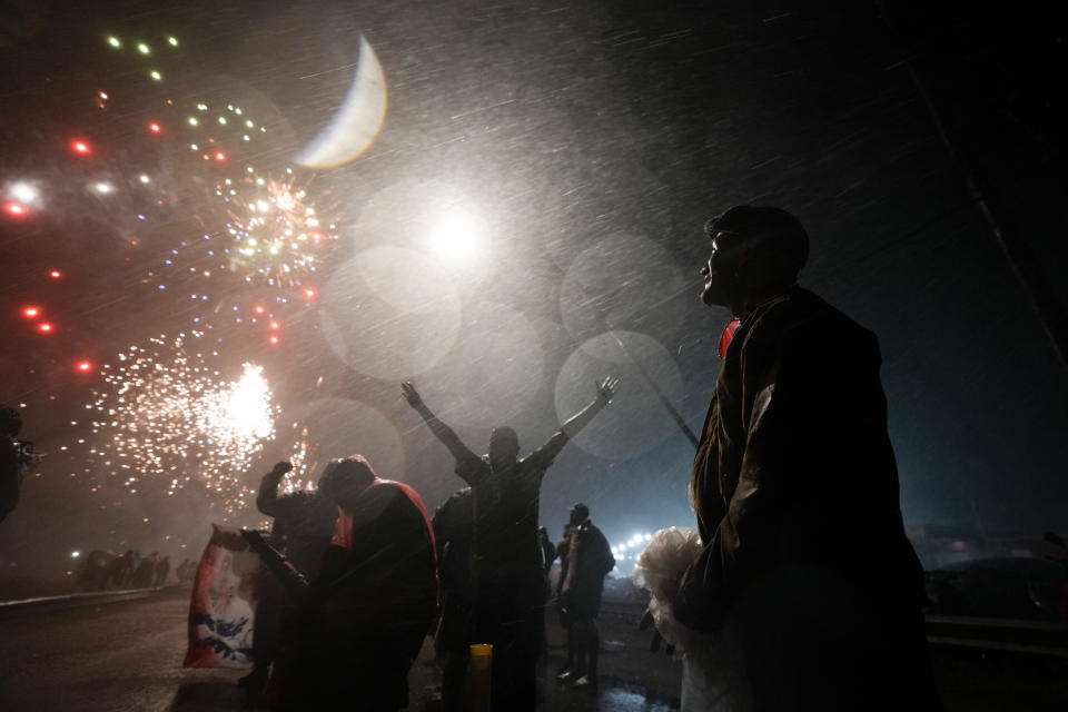 People watch fireworks while rain falls at the folk Saint "Gauchito" Gil sanctuary in Mercedes, Corrientes, Argentina, late Sunday, Jan. 7, 2024. Every Jan. 8, devotees from across the country visit his sanctuary to ask for miracles or give him thanks. (AP Photo/Natacha Pisarenko)