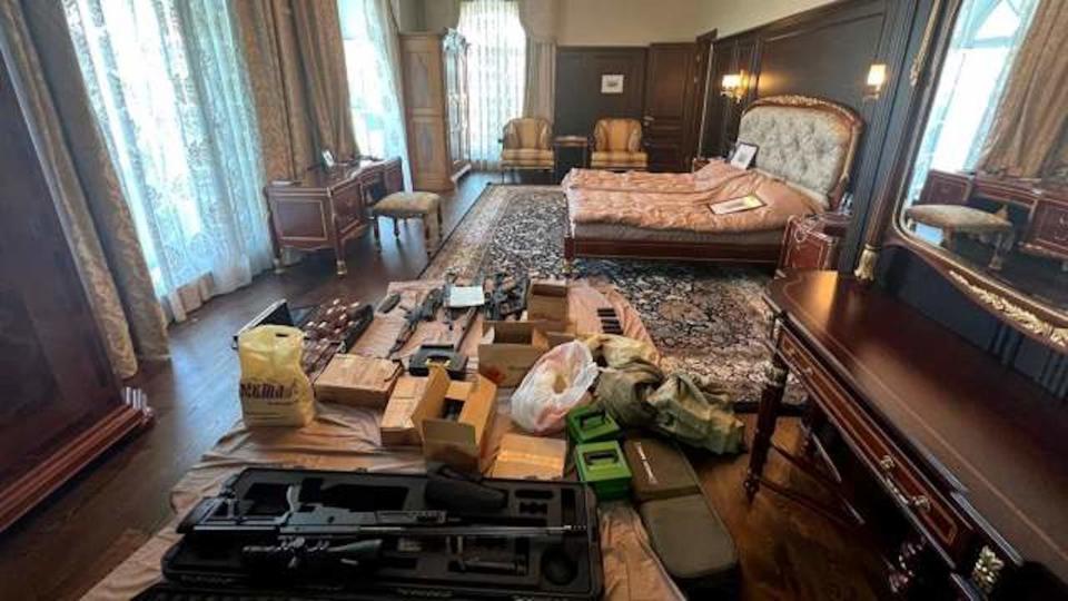 A wood-panelled bedroom with a collection of guns int he foreground.