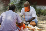 Family member, right, of a person who died of COVID-19 performs Hindu rituals in Prayagraj, India, Saturday, May 15, 2021. India's Prime Minister Narendra Modi on Friday warned people to take extra precautions as the virus was spreading fast in rural areas. (AP Photo/Rajesh Kumar Singh)