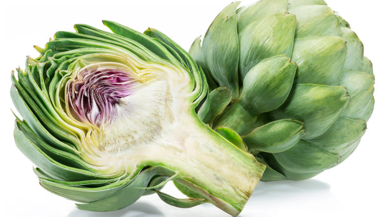 Halved artichoke next to whole artichoke 