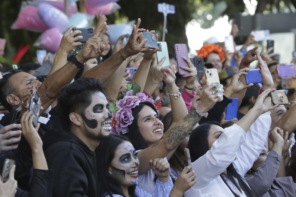 Spectators take pictures of a James Bond-inspired Day of the Dead Parade going past, in Mexico City, Saturday, Nov. 4, 2023. The Hollywood-style parade was adopted in 2016 by Mexico City to mimic a fictitious march in the 2015 James Bond movie “Spectre.” (AP Photo/Ginnette Riquelme)
