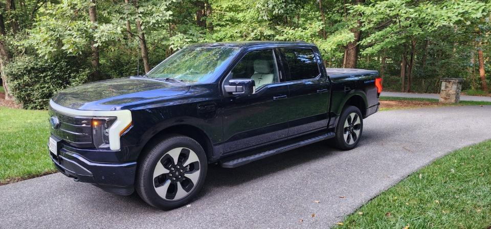 A blue, all-electric Ford 150 Lightning parked in a driveway.