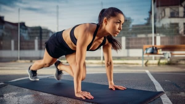 Woman doing mountain climbers outdoors during ab workout