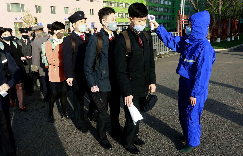 FILE- In this April 22, 2020, file photo, students wearing face masks have their temperature checked as a precaution against the new coronavirus as their university reopened following vacation at the Kim Chaek University of Technology in Pyongyang, North Korea. The coronavirus pandemic appears to be taking a heavy toll on North Korea, forcing its leader Kim Jong Un to sharply shrink his public activities and his people to go on panic buying of daily necessities, South Korea's spy agency told lawmaker Wednesday, May 6, 2020. (AP Photo/Jon Chol Jin, File)