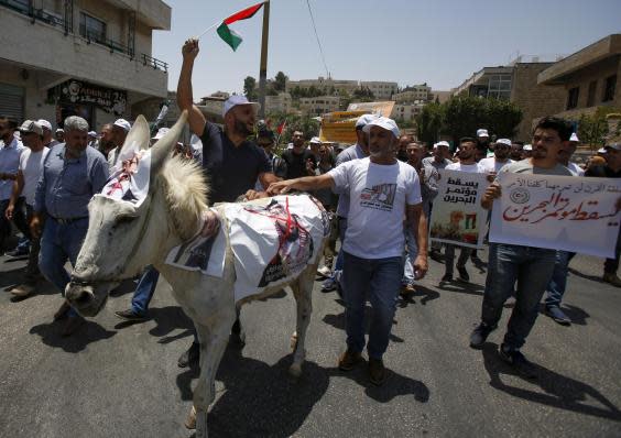 Palestinian demonstrators chant slogans as they walk along a donkey with a photograph of Crown Prince Mohammed bin Salman during protests against a US peace plan (MUSA AL SHAER/AFP/Getty Images)