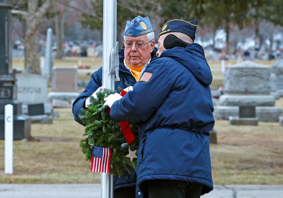 Bulldog John Mersdorf, left, with assistance by Tom Pollock, hang a ceremonial wreath in honor of the United States Marine Corps Division Saturday, Dec. 16, 2023, during a Wreaths Across America ceremony in Tecumseh at Brookside Cemetery.