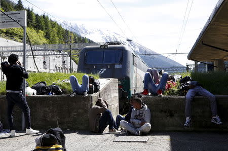 Dejen Asefaw (L), a 24-year-old Eritrean, makes a phone call as he waits at the Brenner railway station, northern Italy, May 28, 2015. REUTERS/Stefano Rellandini