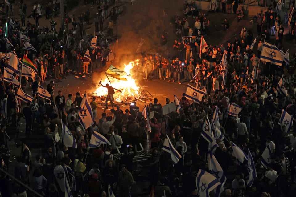 Protesters block a road and hold national flags as they gather around a bonfire during a rally against the Israeli government's judicial reform in Tel Aviv on March 27, 2023.  (Ahmad Gharabli  / AFP - Getty Images)