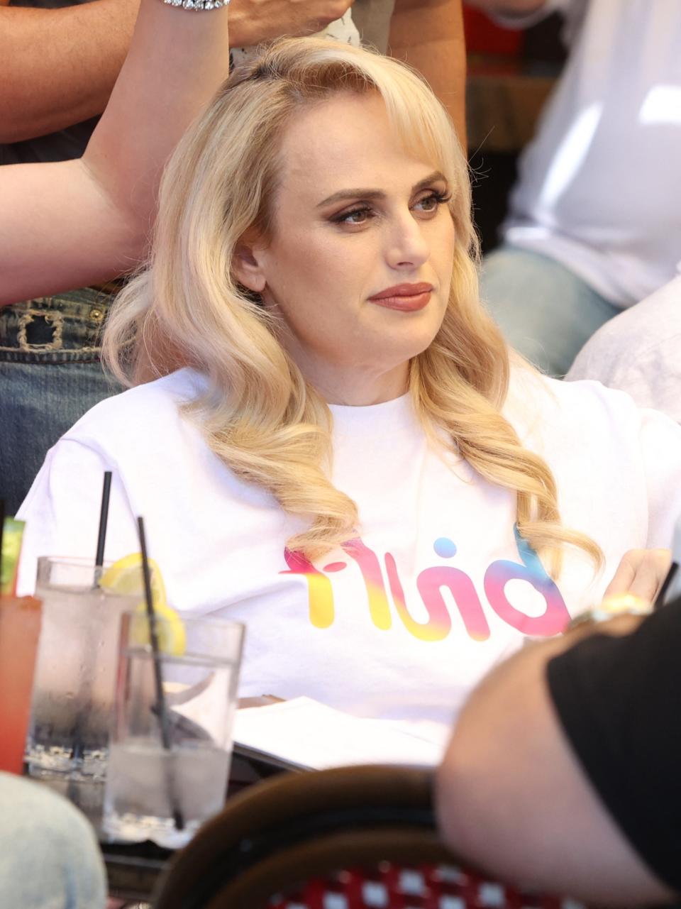 Rebel Wilson wearing a white shirt with 'Rebel' at a sports event