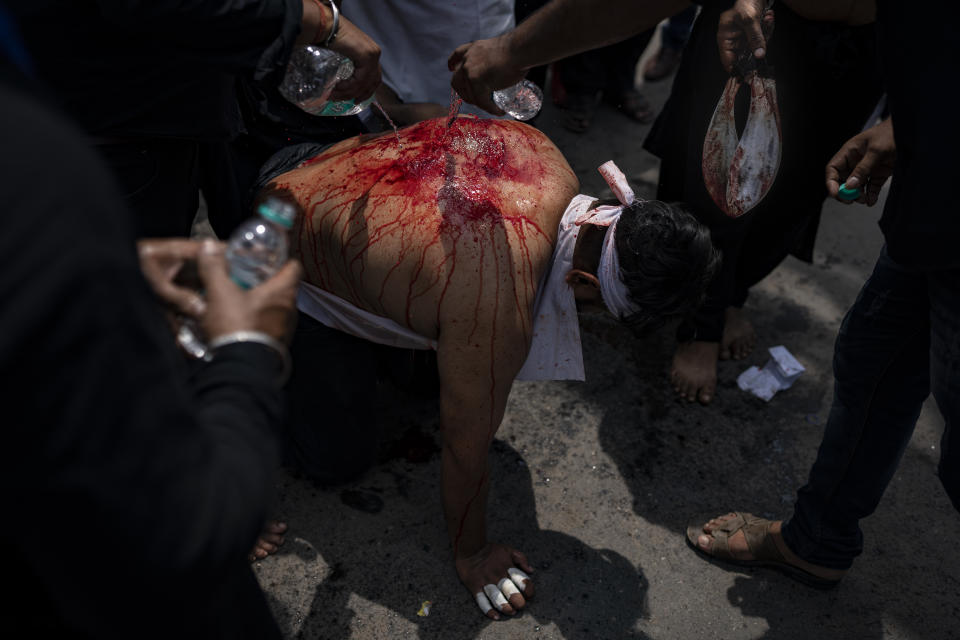 Voluntarios vierten agua sobre el cuerpo sangrante de un musulmán chií después de flagelarse durante una procesión para conmemorar el Ashura en Nueva Delhi, India, el 9 de agosto de 2022. El Ashura conmemora el martirio del imán Hussein, nieto del profeta Mahoma. (AP Foto/Altaf Qadri)