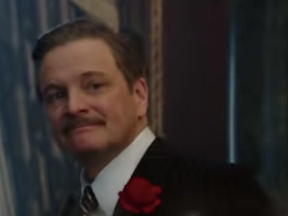 Colin Firth dressed in a suit and with a mustache.