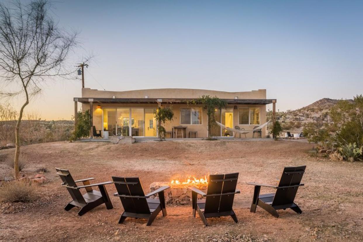 Exterior of a home in Joshua tree with chairs around firepit