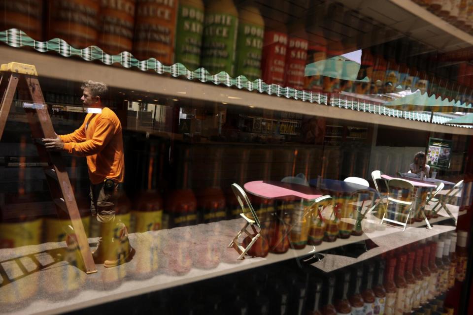 A worker is reflected in the storefront window of a store