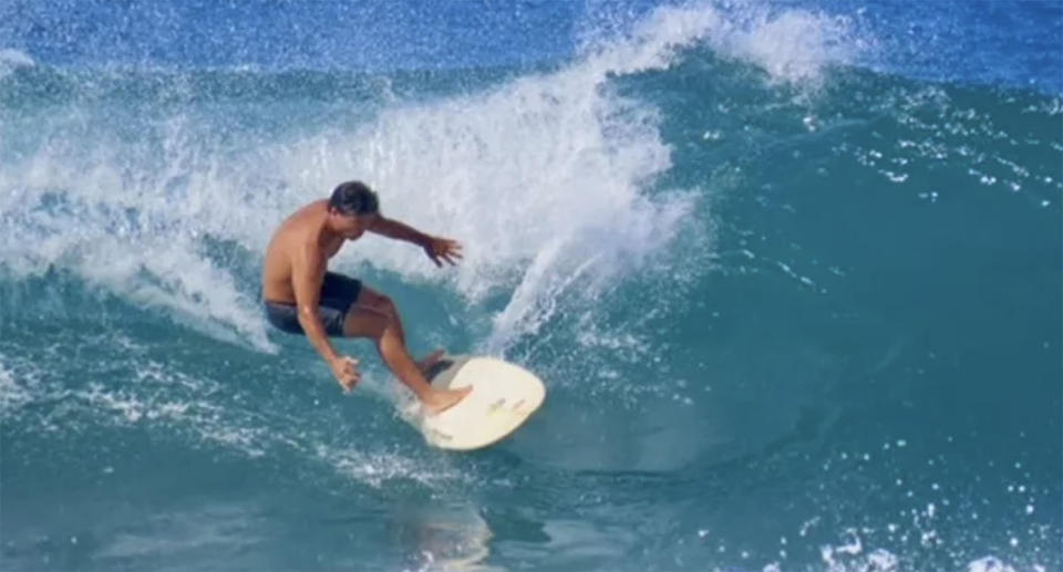 Mike Morita rides a surfboard on a wave in Hawaii.