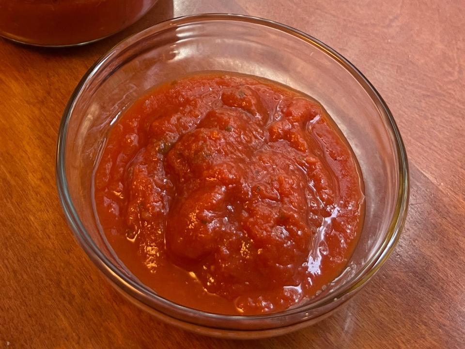 Barilla marinara sauce in a glass bowl next to a jar on a wooden table