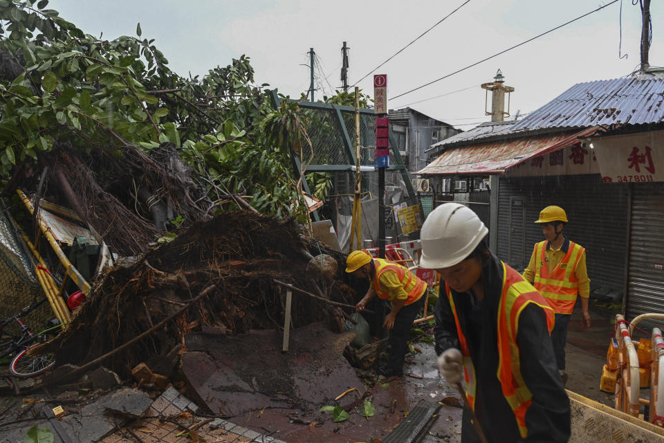 Workers clear debris near shophouses after Typhoon Saola struck the city with strong winds and rain, in Hong Kong, Saturday, Sept. 2, 2023. The typhoon made landfall in southern China before dawn Saturday after nearly 900,000 people were moved to safety and most of Hong Kong and other parts of coastal southern China suspended business, transport and classes. (AP Photo/Billy H.C. Kwok)