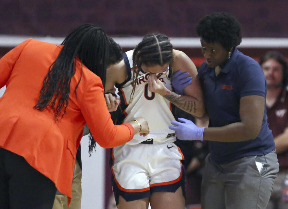 Virginia's Olivia McGhee (0) is escorted from the court after an injury in the first half of an NCAA basketball game against Virginia Tech, Thursday, Feb. 1, 2024, in Blacksburg, Va. (Matt Gentry/The Roanoke Times via AP)