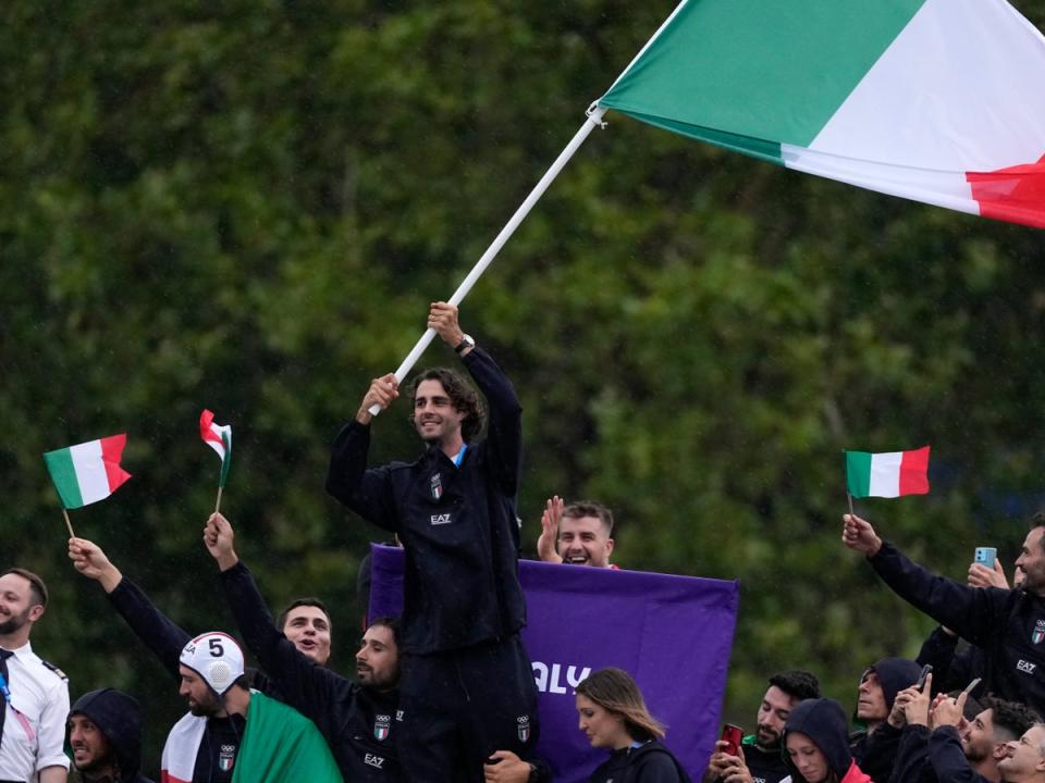 Gianmarco Tamberi waves an Italian flag as the Italian team parades along the Seine river in Paris (AP)