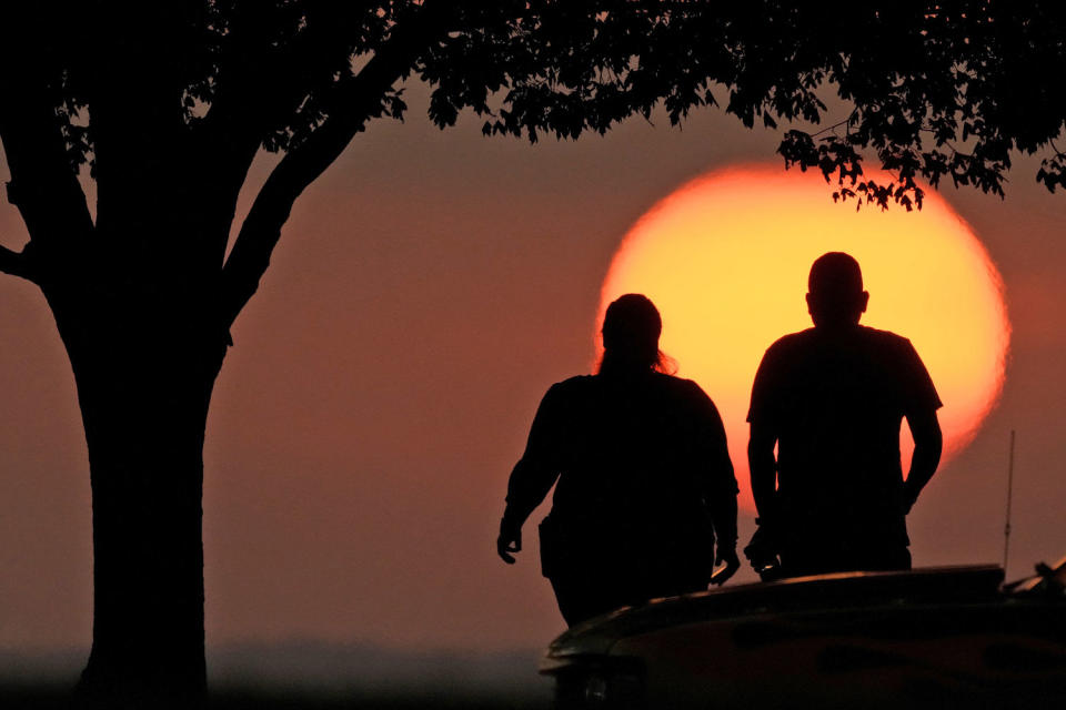 A couple watches the sunset as triple-digit heat indexes continue in the Midwest Sunday, Aug. 20, 2023, in Kansas City, Mo.  (Charlie Riedel / AP)