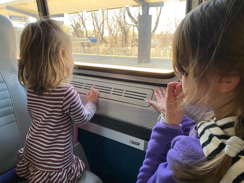 two kids looking out the window of an amtrak train