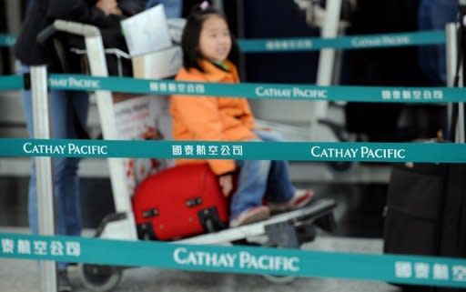 Passengers line up to check in at an arrivals desk for Cathay Pacific at Hong Kong's international airport. Passenger revenue for the year rose 14.2 percent to HK$67.78 billion. Cathay carried a total of 27.6 million passengers last year, a rise of 2.9 percent from 2010, as demand for premium class travel remained robust