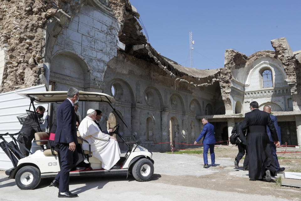 Pope Francis, sitting in a cart, is shown the devastation of the Syriac Catholic Al-Tahera church near Hosh al-Bieaa Church Square where he led a prayer session in Mosul, Iraq, once the de-facto capital of IS, Sunday, March 7, 2021. The long 2014-2017 war to drive IS out left ransacked homes and charred or pulverized buildings around the north of Iraq, all sites Francis visited on Sunday. (AP Photo/Andrew Medichini)