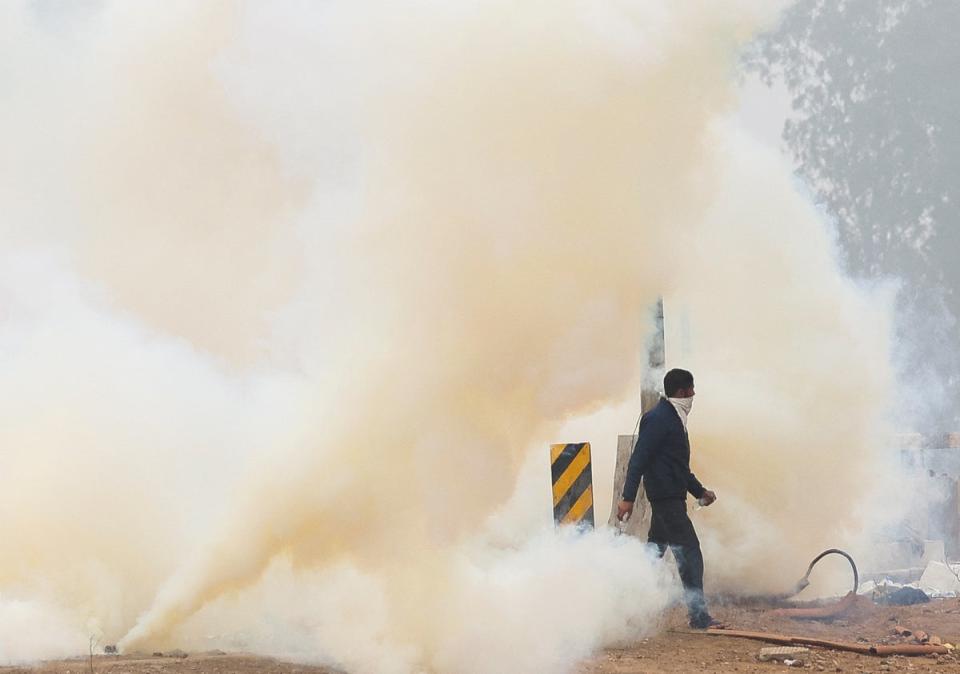 A man walks through tear gas at the site of the protest, as farmers march towards New Delhi to press for better crop prices promised to them in 2021, at Shambhu barrier, a border crossing between Punjab and Haryana states, India, 21 February 2024 (Reuters)