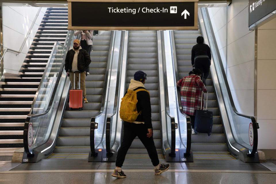 Travelers ride escalators in a terminal at Ronald Reagan Washington National Airport in Arlington, Va., Wednesday, Nov. 23, 2022. (AP Photo/Patrick Semansky)