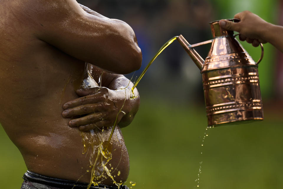 A wrestler is doused in oil by an 'oiler, during the 663rd annual Historic Kirkpinar Oil Wrestling championship, in Edirne, northwestern Turkey, Saturday, July 6, 2024. Wrestlers take part in this "sudden death"-style traditional competition wearing only a pair of leather trousers and a good slick of olive oil. The festival is part of UNESCO's List of Intangible Cultural Heritages. (AP Photo/Khalil Hamra)