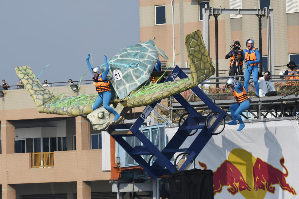 A team member jumps from a platform with a man made flying machine into the harbor in Taichung, a port city in central Taiwan on Sunday, Sept. 18, 2022. Pilots with homemade gliders launched themselves into a harbor from a 20-foot-high ramp to see who could go the farthest before falling into the waters. It was mostly if not all for fun as thousands of spectators laughed and cheered on 45 teams competing in the Red Bull “Flugtag” event held for the first time. (AP Photo/Szuying Lin)