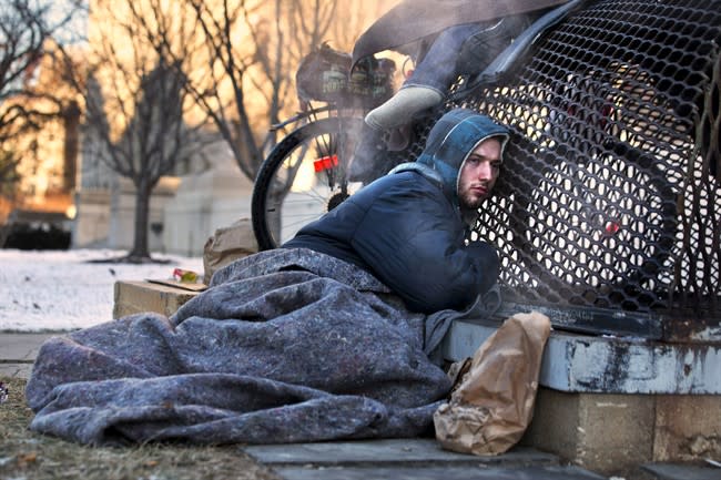 Nick warms himself on a steam grate with three other homeless men by the Federal Trade Commission, just blocks from the Capitol, during frigid temperatures in Washington, Saturday, Jan. 4, 2014. A winter storm that swept across the Midwest this week blew through the Northeast on Friday, leaving bone-chilling cold in its wake. (AP Photo/Jacquelyn Martin)