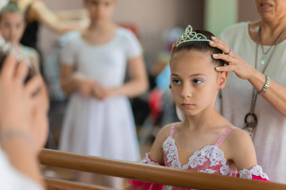 Serious little girl looking in the mirror in a dance studio